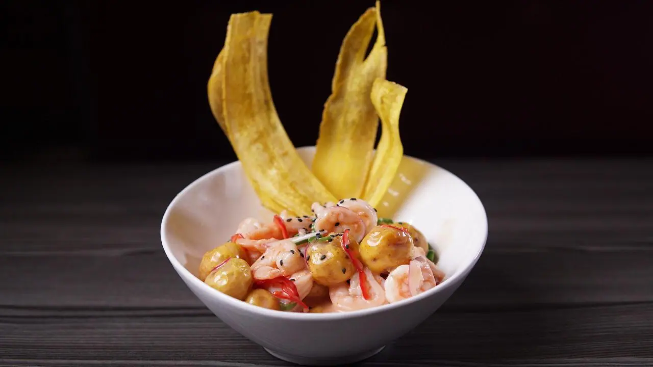 Ceviche de camarón con chips de plátano servido en bol blanco